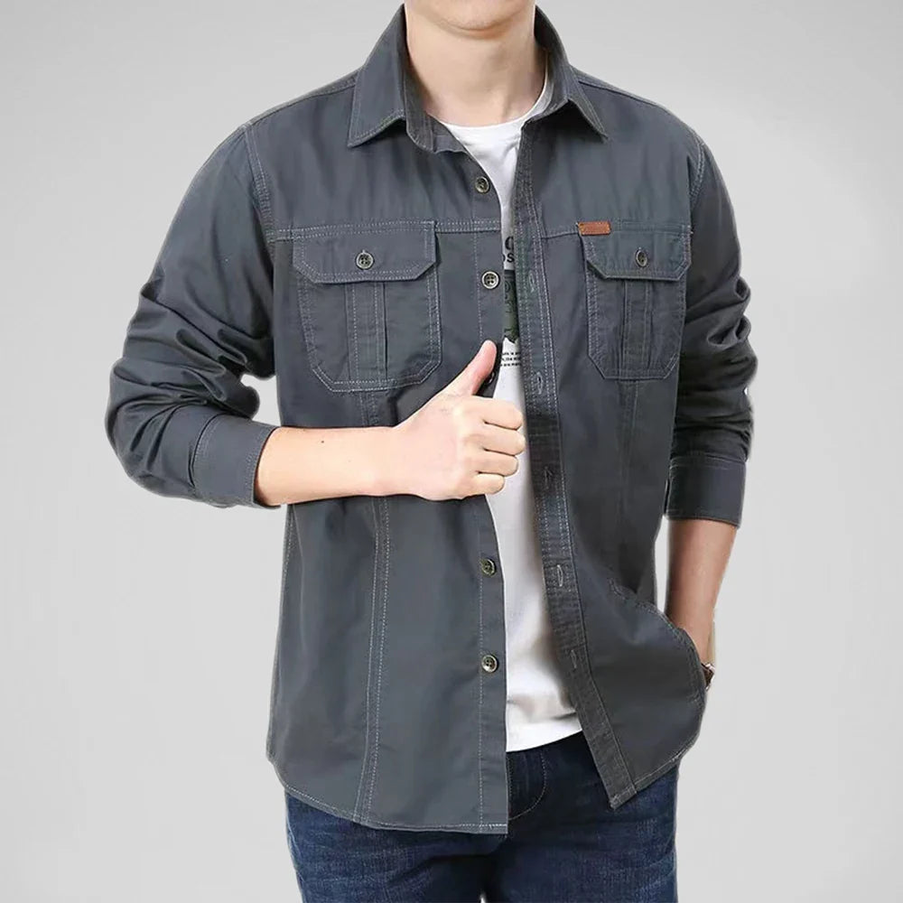 Person wearing a dark gray button-up shirt over a white shirt on a light gray background