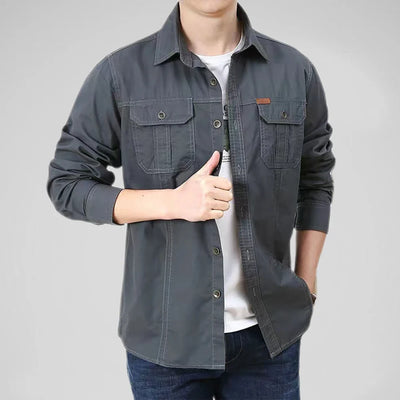 Person wearing a dark gray button-up shirt over a white shirt on a light gray background